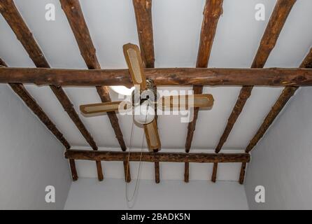 Sloped residential home ceiling with thick wooden beams and an electrical fan image in horizontal format Stock Photo