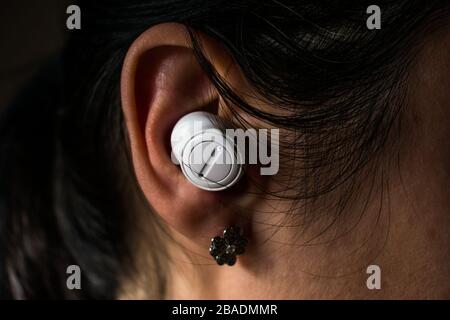 Woman ear with white wireless earbud Stock Photo