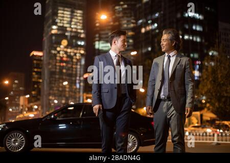 Successful Chinese businessmen talking on city street Stock Photo