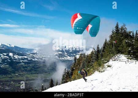 A paraglider taking off from the hillside below Chaine des Fiz, alpine mountains in the French Alps Stock Photo