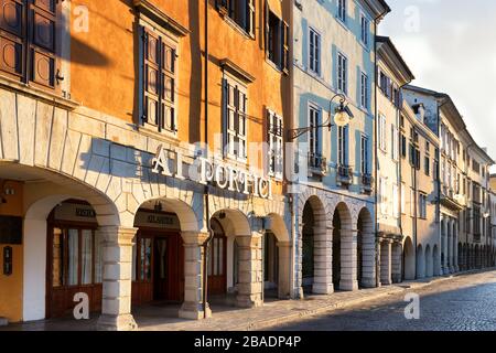 Portico and houses facing on a cobblestone street in Udine city center. Beautiful Italian classic architecture example. Italy. Stock Photo