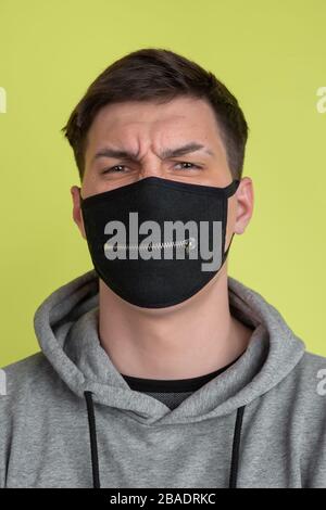 Hard thinking. Caucasian man's portrait isolated on yellow studio background. Freaky model in black face mask. Concept of human emotions, facial expression, sales, ad. Unusual appearance. Stock Photo