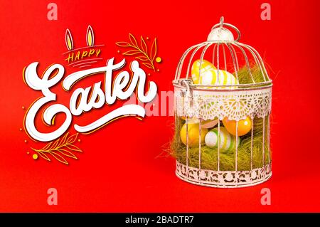 White bird cage with Easter eggs in it on a red background Stock Photo