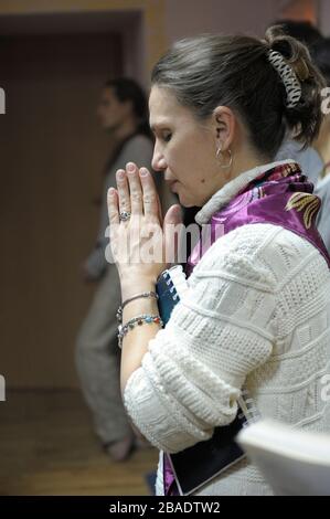 Young female Hare Krishna parishioner praying in a temple Stock Photo