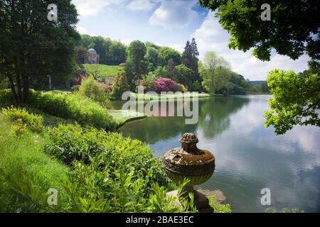 The brilliant spring colours of rhododendrons and azaleas below the Temple of Apollo at Stourhead Gardens, Wiltshire, England, UK Stock Photo