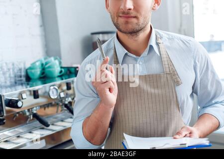 Young adult barista working in restaurant, making notes Stock Photo