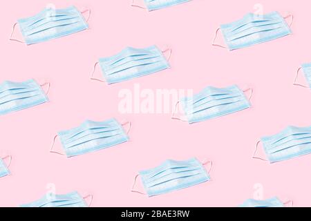 Pattern made of blue medical masks on pink background. Protection against virus concept. Stock Photo