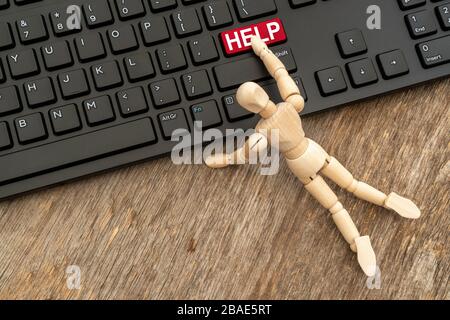 Online HELP button. Wooden dummy pressing HELP button on a computer keyboard. Stock Photo