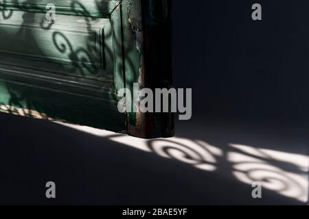 Old wooden window shutter (blind) detail with Moroccan window grid shadows. Dark background image. Stock Photo