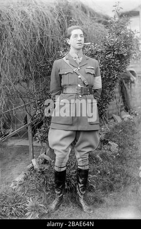 A vintage black and white photograph taken in 1917,  showing a young male pilot of the British Royal Flying Corps, during the First World War,  in full uniform wearing a monocle, and smoking a cigarette in a holder. Photo is taken in the garden of a private house in England. Stock Photo