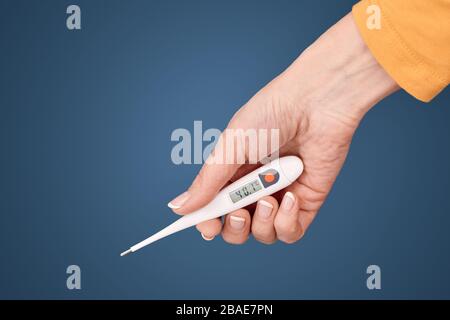 Middle aged woman holding electronic thermometer in hand Stock Photo