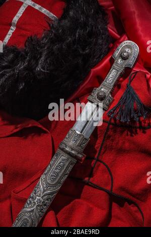 Beautiful example of caucasian dagger on red cossack beshmet background. 19th century (Time of Russian-Caucasian wars (1816-1864)). Russia Stock Photo