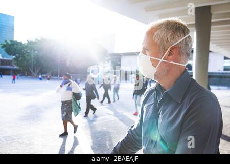 Middle aged man wearing coronavirus Covid 19 mask on the go