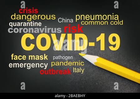 COVID-19 awareness word cloud surrounded by a relevant word cloud with yellow pencil besides. Coronavirus alert concept Stock Photo
