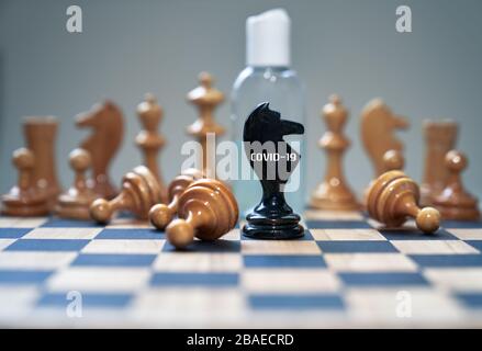 Coronavirus concept image chess pieces and hand sanitizer on chessboard illustrating global struggle against novel covid-19 outbreak. Stock Photo