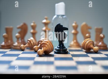 Coronavirus concept image chess pieces and hand sanitizer on chessboard illustrating global struggle against novel covid-19 outbreak. Stock Photo