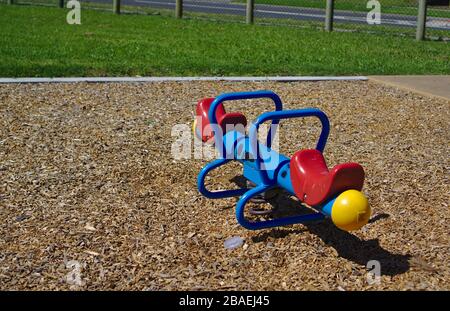Children see saw in red, blue, and yellow colors on brown wooden pieces ground Stock Photo