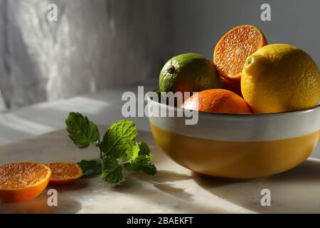 Still life with orange fruit and mint  on white marble top and canvas. Stock Photo