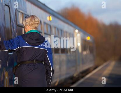 Arriva Northern rail guard / conductor closing the doors on a train before departure from Morecambe railway station Stock Photo