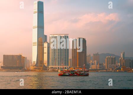 Central, Hong Kong - March 1, 2020: Star ferry and skyscrapers with the sunset in Victoria Harbour Stock Photo