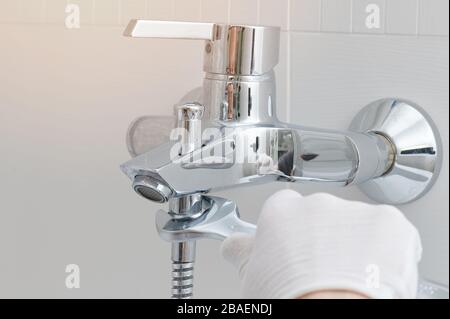 Fixing faucet in bathroom. Hand with wrench installing tap Stock Photo