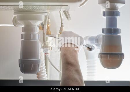 Hand with wrench fixing sink pipe close up view Stock Photo