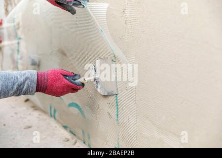construction worker installing fiberglass plaster mesh on the wall Stock Photo