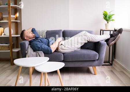 Portrait Of Tired Man Sleeping On Couch Stock Photo