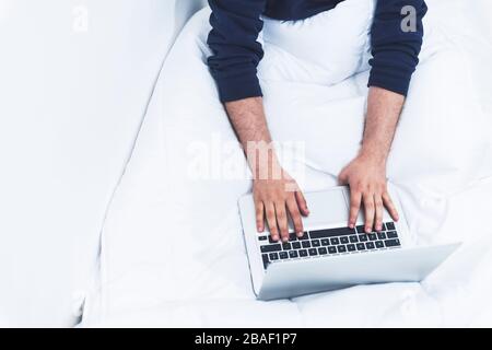 top view of a man working on his lap top the the bed Stock Photo