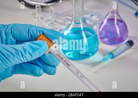 Hands in blue gloves holding testing kit. Medical flasks, colorful chemical reagents. Ampoules with liquid, syringe, phonendoscope isolated on white. Stock Photo