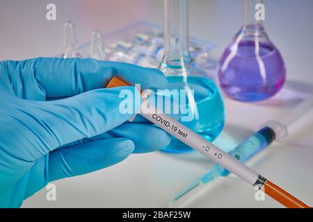 Hands in blue disposable gloves holding testing kit. Medical flasks with colorful chemical reagents. Ampoules with liquid and syringe isolated on whit Stock Photo