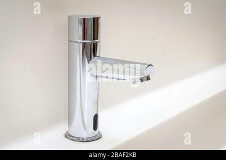 Steel modern design steel faucet with a running water flow. Wash hands, novel coronavirus COVID 19 spread prevention, health ministry regulations Stock Photo
