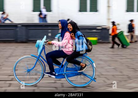 Young Indonesian Women Cycling In Taman Fatahillah Square, Jakarta, Indonesia. Stock Photo