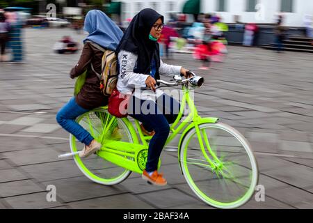 Young Indonesian Women Cycling In Taman Fatahillah Square, Jakarta, Indonesia. Stock Photo