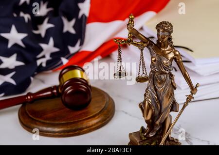 Figure of Justice holding the scales of justice with gavel on a law paper documents in against blurred USA flag Stock Photo