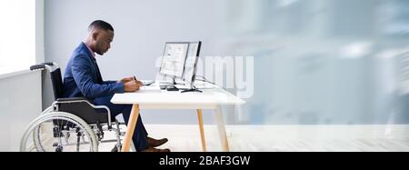 Disabled African Accountant Working On Computer In Wheelchair Stock Photo