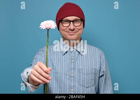 Young caucasian man holding flower. Anniversary present concept Stock Photo