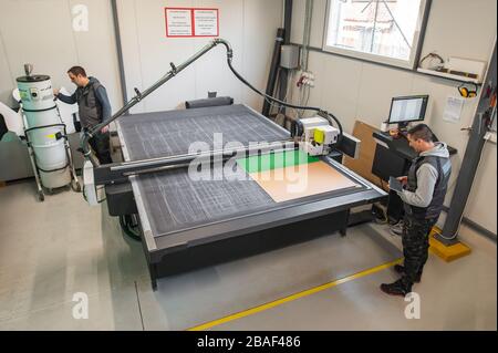 Two printshop worker technicians works on large CNC computer numerical control printing and cutting machine Stock Photo
