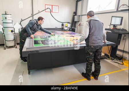 Two printshop worker technicians works on large CNC computer numerical control printing and cutting machine Stock Photo