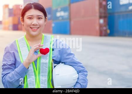 Girl teen worker in cargo container shipping port working with heart and good service mind concept. Stock Photo
