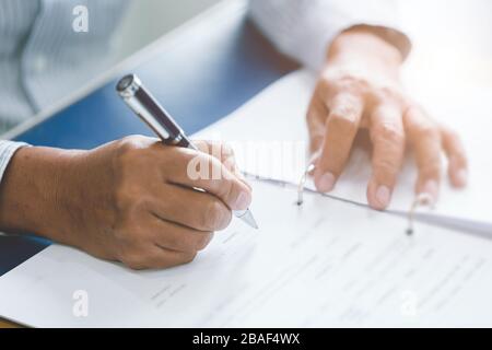 closeup elder hand writing paper working with ball pen in office desk. Stock Photo