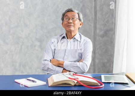 Chinese doctor sitting in the office desk with book happy smile healthy strong. Stock Photo