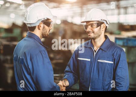 Worker engineer team smiling handshake for finish working dealing job done in factory industry background. Stock Photo