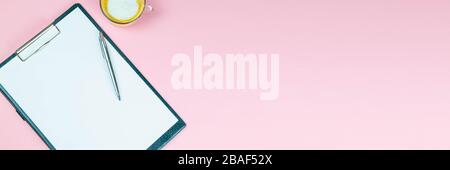 Tablet with a white sheet on which there is a silver pen and next to there is a glass with a coffe with milk Stock Photo