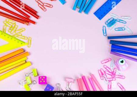 Multi-colored pencils rulers, pens, pencils and scissors and stationery stand on a pink background Stock Photo