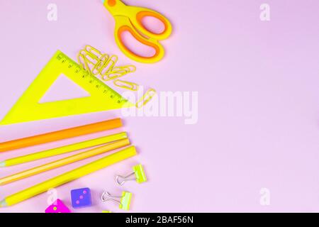 Multi-colored red yellow pinc pencils rulers, pens, pencils and scissors and stationery stand on a pink background Stock Photo
