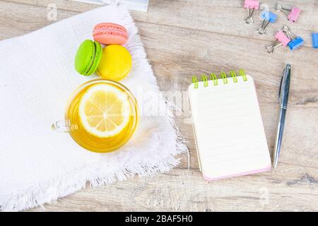 An open notebook with a silver pen, a cup of mint tea with lemon and multi-colored muffins stand next to it Stock Photo
