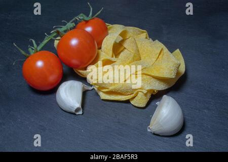 Raw ingredients: cherry tomatoes, dry pasta, basil leaves garlic Stock Photo
