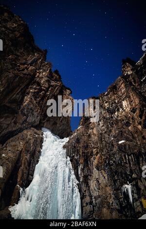 Frozen waterfall in the winter night mountain at starry sky with Big Dipper constellation Stock Photo