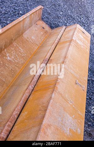 Two sheet pile wall elements lie on a bridge construction site on gravel ground and are joined together, dynamic perspective and selective focus Stock Photo